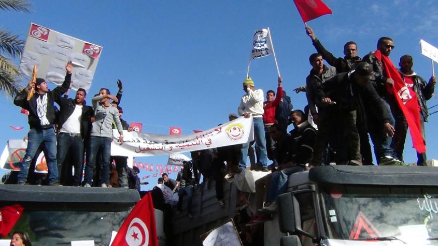 Tunisians wave banners and their national flag while they shout slogans against the country's ruling Islamist Ennahda party, on November 27, 2013 in the central Tunisian town of Gafsa, as a general strike was called to protest against poverty and lack of development. Angry protesters set fire to the Ennahda party in the neglected Gafsa region, as strikes were observed in areas amid rising discontent and political deadlock. AFP PHOTO / STR        (Photo credit should read STR/AFP/Getty Images)