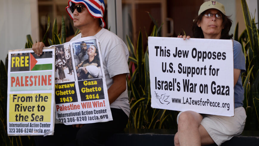 A Jewish peace activist (R) watches a rally by Palestine Americans and their supporters during their protest march against the ongoing conflict in Gaza on August 16, 2014 in Los Angeles.  Israel secured supplies of ammunition from the Pentagon last month without the approval of the White House or the State Department. President Barack Obama's administration, caught off guard as it tried to restrain Israel's campaign in Gaza, has since tightened controls on arms shipments to Israel.      AFP PHOTO/Mark RALST