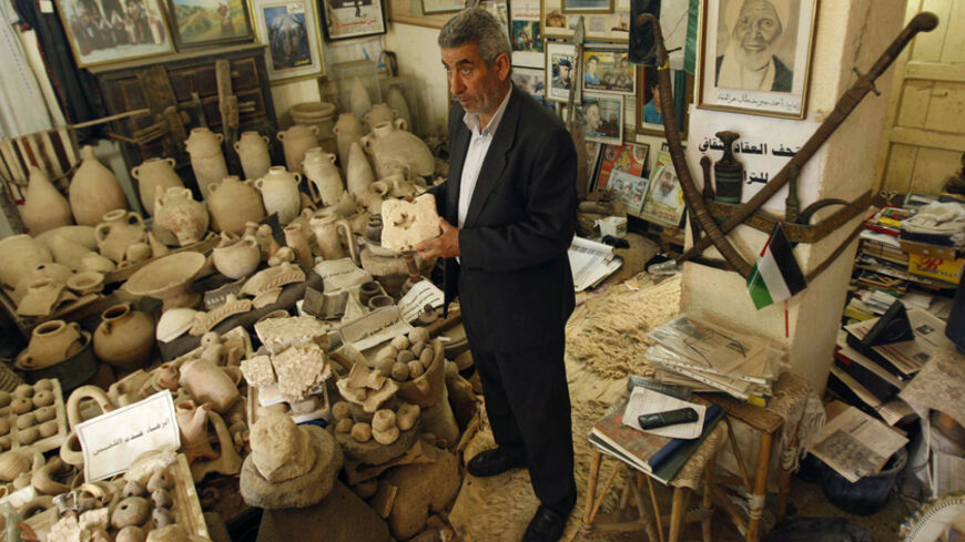 Palestinian amateur archaeologist Waleed Al-Aqqad shows his collection of ancient artefacts at his house, which he was turned into a museum, in Khan Younis in the southern Gaza Strip April 3, 2011. Five thousand years of fascinating history lie beneath the sands of the Gaza Strip, from blinded biblical hero Samson to British general Allenby. Picture taken April 3, 2011. To match Feature PALESTINIANS-ARCHAEOLOGY      REUTERS/Ibraheem Abu Mustafa (GAZA  - Tags: ENTERTAINMENT)   - RTR2LFVJ