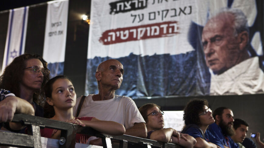 Israelis take part in a mass rally marking the 17th anniversary of the assassination of former Israeli prime minister Yitzhak Rabin, in Tel Aviv October 27, 2012. Israel on Saturday marked the 17th anniversary of Rabin's assassination by an ultra-nationalist Jew. The words in Hebrew near Rabin's photo read "Remembering the murder, fighting for democracy". REUTERS/ Nir Elias (ISRAEL - Tags: POLITICS ANNIVERSARY) - RTR39NVH