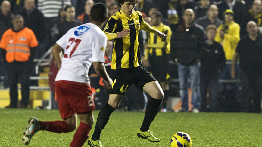 Beitar Jerusalem's new player Dzhabrail Kadiyev (R) plays during a match against Bnei Sakhnin as part of the Israeli Premier League, at Teddy Stadium in Jerusalem February 10, 2013. There was heightened security at Sunday's match following last week's arraignment of four fans in connection with racist incitement against the team's recruitment of Muslim players. REUTERS/Nir Elias (JERUSALEM - Tags: SPORT SOCCER POLITICS) - RTR3DLJ2