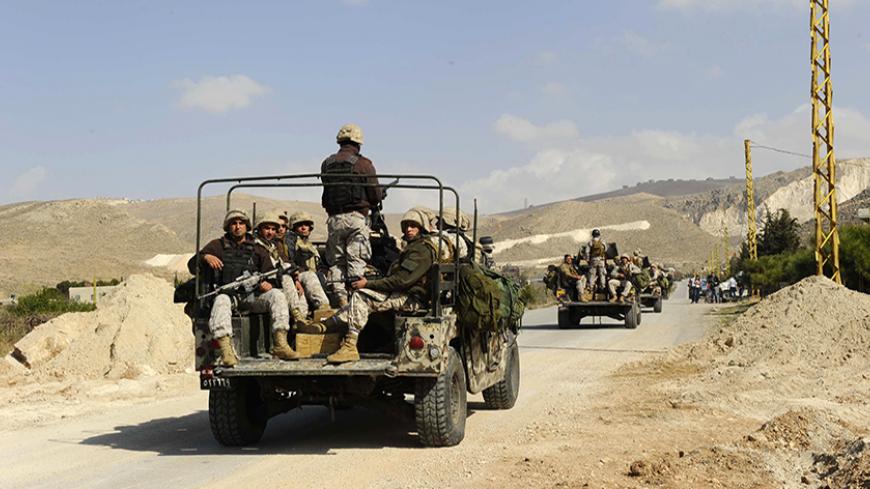 Lebanese army soldiers on their military vehicles enter the Sunni Muslim border town of Arsal, in eastern Bekaa Valley March 19, 2014. The Lebanese army reopened a road between two towns near the Syrian border on Wednesday to try to calm sectarian rivalry aggravated by the conflict in neighbouring Syria. Shi'ite Muslims from the Bekaa Valley town of al-Labwa, where Hezbollah has strong support, had erected sandbag barriers at the weekend to cut off the Sunni Muslim town of Arsal from the rest of Lebanon. RE