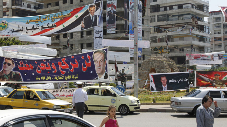 Election posters of Syria's President Bashar al-Assad hang along a street and on buildings in Latakia city May 24, 2014. Syria is holding an election in June that looks all but certain to give President Bashar al-Assad a third seven-year term. REUTERS/Khaled al-Hariri (SYRIA - Tags: POLITICS CONFLICT CIVIL UNREST ELECTIONS) - RTR3QO2K