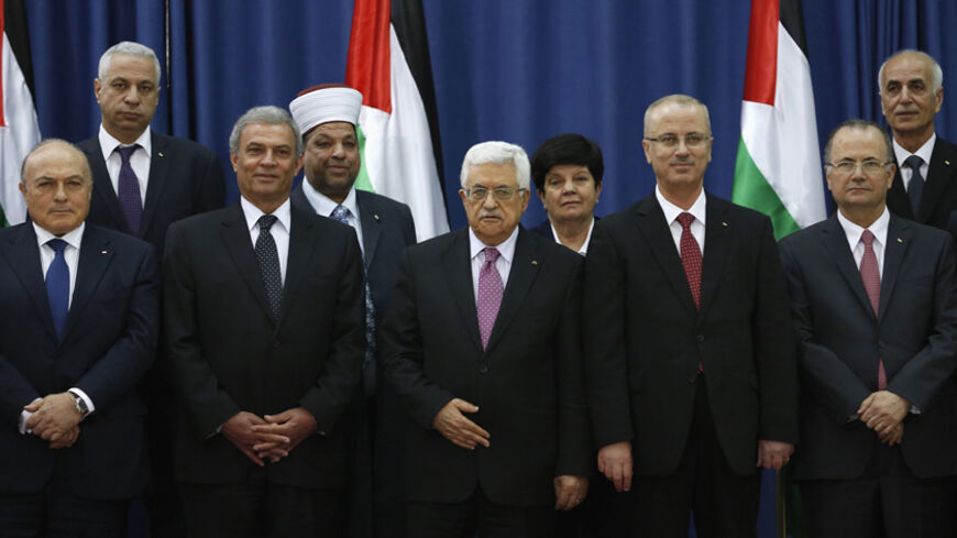 Palestinian Prime Minister Rami Hamdallah (4th L) and Palestinian President Mahmoud Abbas (3rd L) pose for a group photo with Palestinian ministers during a swearing-in ceremony of the unity government, in the West Bank city of Ramallah June 2, 2014. Abbas swore in a unity government on Monday after overcoming a last-minute dispute with the Hamas Islamist group. REUTERS/Mohamad Torokman (WEST BANK - Tags: POLITICS) - RTR3RT7N