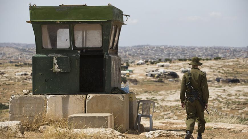 An Israeli soldier guards the West Bank Jewish settlement of Susia, south of Hebron May 19, 2014. Israeli lawmakers are pressing Prime Minister Benjamin Netanyahu to lift what they call unjustified secrecy over opaque - and rising - funding for settlements on West Bank land Palestinians want for a state. Picture taken May 19, 2014. REUTERS/Amir Cohen (WEST BANK - Tags: POLITICS BUSINESS MILITARY) - RTR3VEDO