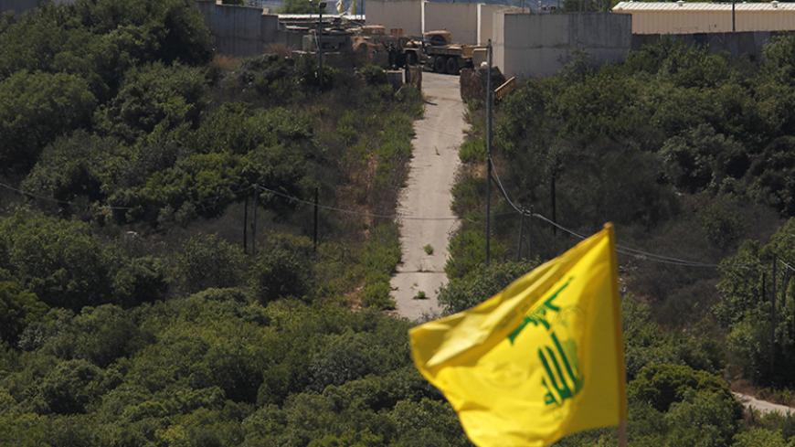 Israeli soldiers and trucks are seen from the southern Lebanese village Marwaheen, as a Hezbollah flag flutters during a protest in solidarity with Palestinian people in Gaza near the Lebanese-Israeli border July 25, 2014. The protest was organised by Hezbollah with the participation of Shi'ite and Sunni Muslim Sheikhs, against Israel's military action in Gaza and marking the annual al-Quds Day. REUTERS/Ali Hashisho   (LEBANON - Tags: POLITICS CIVIL UNREST RELIGION MILITARY) - RTR403PX