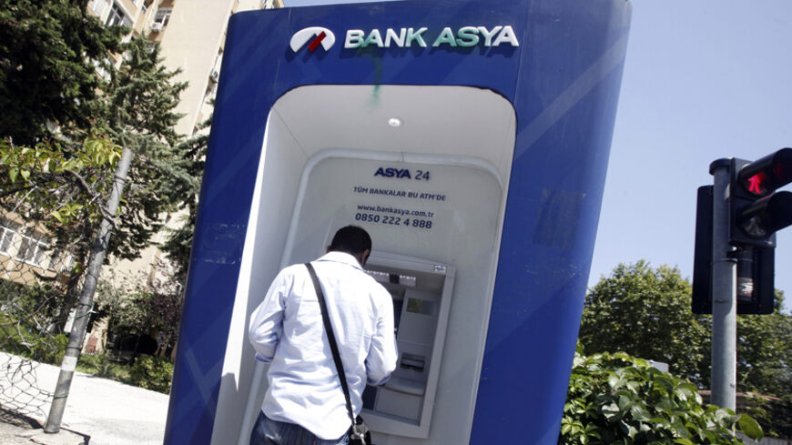 A man uses an ATM machine of Bank Asya in Istanbul August 12, 2014. Turkish Islamic lender Bank Asya said its second-quarter net profit fell 81 percent to 10.6 million lira ($4.9 million) as its deposit base shrank and lending wilted under pressure from the government. The lender has seen its profits and capital base collapse since December when it found itself at the centre of a power struggle between Prime Minister Tayyip Erdogan and his political foe Fethullah Gulen, an Islamic cleric whose sympathisers 