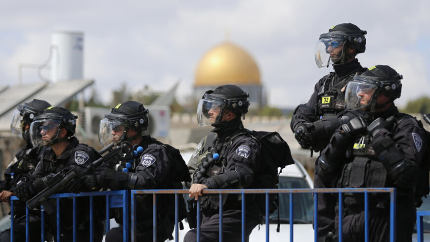 The Dome of the Rock is seen in the background as Israeli policemen stand guard before Palestinian men begin to pray in the Arab East Jerusalem neighbourhood of Ras al-Amud  September 26, 2014. Israeli police declared an age limit on Friday for Palestinians wanting to enter the Old City, only allowing males above the age of 50 and all females to enter. REUTERS/Ammar Awad (JERUSALEM - Tags: CIVIL UNREST POLITICS) - RTR47U0S