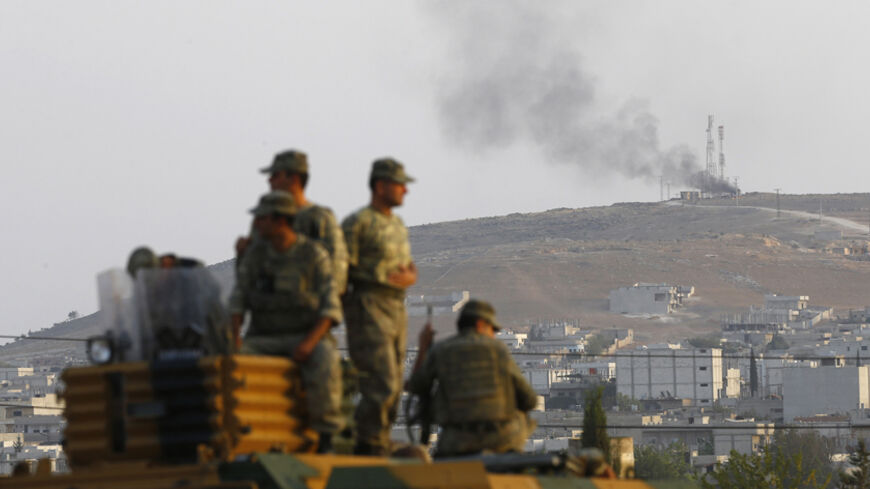 Turkish soldiers are seen on top of an armoured vehicle, with the Syrian town of Kobani in the background, near the Mursitpinar border crossing on the Turkish-Syrian border, in the southeastern Turkish town of Suruc in Sanliurfa province October 3, 2014. Kurdish fighters defending a Syrian border town warned on Friday of a likely massacre by Islamic State insurgents as the Islamists encircled the town with tanks and bombarded its outskirts with artillery fire. Turkey said it would do what it could to preven