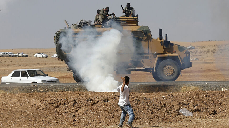 A protester throws stones at an armoured army vehicle during a pro-Kurdish demonstration in solidarity with people of Kobani, near the Mursitpinar border crossing on the Turkish-Syrian border, in the Turkish town of Suruc in southeastern Sanliurfa province October 7, 2014. Islamic State fighters advanced into the south west of the Syrian Kurdish town of Kobani overnight, a monitoring group said on Tuesday, taking several buildings to gain attacking positions from two sides of the city.  REUTERS/Umit Bektas 