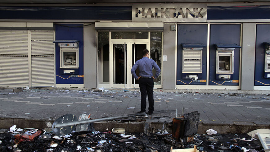 A man looks at a damaged branch of Halkbank, set on fire during clashes between Kurdish protesters and riot police overnight, in Diyarbakir October 8, 2014. At least 12 people died on Tuesday during violent clashes across Turkey, local media reported, as the fate of the besieged Syrian border town of Kobani stirred up decades of tensions with Turkey's Kurdish minority. Violence erupted in Turkish towns and cities mainly in the Kurdish southeastern provinces, as protesters took to the streets to demand the g
