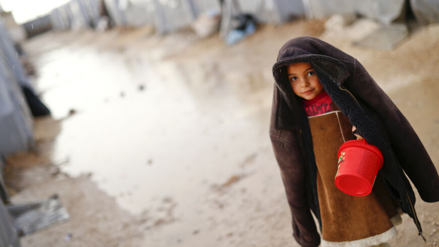 A Kurdish refugee child from the Syrian town of Kobani walks in the rain in a camp in the southeastern town of Suruc, Sanliurfa province, October 16, 2014. The United States is bombing targets in Kobani for humanitarian purposes to relieve defenders of the Syrian town and give them time to organize against Islamic State militants, a senior U.S. official said on Wednesday. REUTERS/Kai Pfaffenbach (TURKEY  - Tags: MILITARY CONFLICT POLITICS)  - RTR4AFUO