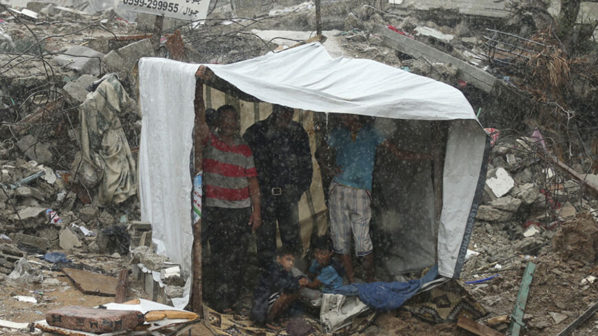 Palestinians take cover from rain inside a makeshift shelter near the ruins of their houses, that witnesses said were destroyed during a seven-week Israeli offensive, in the east of Gaza City October 19, 2014.  An open-ended ceasefire between Israel and Hamas-led Gaza militants, mediated by Egypt, took effect on August 26 after a seven-week conflict. It called for an indefinite halt to hostilities, the immediate opening of Gaza's blockaded crossings with Israel and Egypt, and a widening of the territory's f