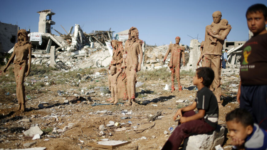 Palestinian boys look at statues that are made of fiberglass and covered with clay by Palestinian artist Eyad Sabbah, which are depictions for the Palestinians who fled their houses from Israeli shelling during the most recent conflict between Israel and Hamas, in the east of Gaza City October 21, 2014. REUTERS/Mohammed Salem (GAZA - Tags: CIVIL UNREST POLITICS SOCIETY) - RTR4AXXF
