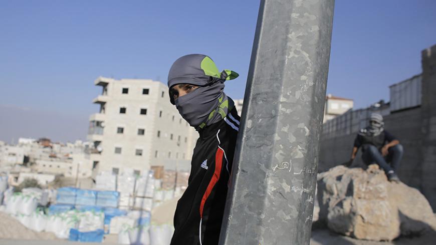 A Palestinian stone-thrower takes cover behind a street pole during clashes with Israeli police in the east Jerusalem neighbourhood of Issawiya October 23, 2014. Tension in Jerusalem rose on Wednesday after an Israeli baby died and eight other people were hurt when a Palestinian man slammed his car into pedestrians at a Jerusalem light railway stop. Police shot the driver as he fled. A hospital official said the driver later died of his injuries. REUTERS/Ammar Awad (JERUSALEM - Tags: POLITICS CIVIL UNREST) 