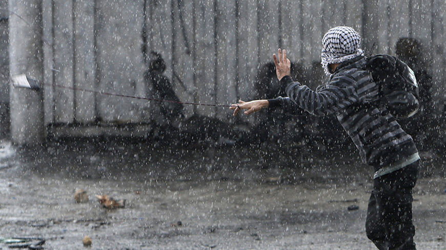 A masked Palestinian protester uses a sling shot to throw stones at Israeli troops during clashes, following an anti-Israel demonstration over the entry restrictions to the al-Aqsa mosque, on a rainy day at Qalandia checkpoint near the West Bank city of Ramallah October 31, 2014. Muslim men over 50 prayed at the Aqsa mosque in Jerusalem's Old City on Friday amid intense security, a day after Israel closed all access to the sacred compound for the first time in more than a decade following violence on the st