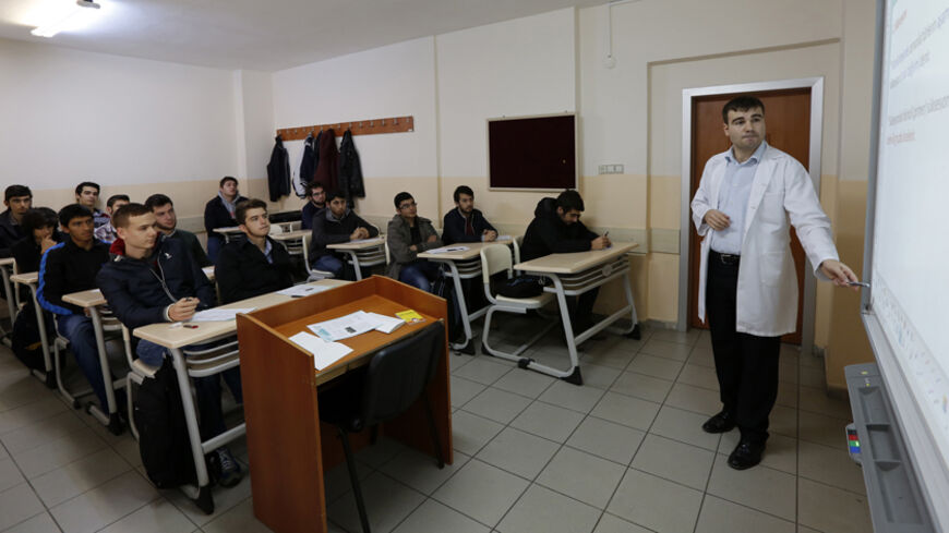 A teacher points to the board as he teaches students during a class at FEM University Preparation School in Uskudar November 27, 2013. At the FEM University Preparation School in Uskudar, a conservative district on the Asian side of Istanbul, young men are quietly receiving specialised coaching in how to pass the exams that give access to the most important jobs in Turkey. To a casual eye, nothing seems remarkable. As in nearly all Turkish schools, a portrait of Ataturk hangs in every classroom. There are n