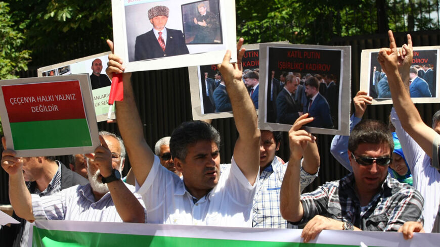 Protestors hold images of Medet Unlu, a Chechen activist based in Turkey who was killed on May 22 as they protest his death outside the Russian embassy in Ankara on May 25, 2013. 
AFP PHOTO/ADEM ALTAN        (Photo credit should read ADEM ALTAN/AFP/Getty Images)