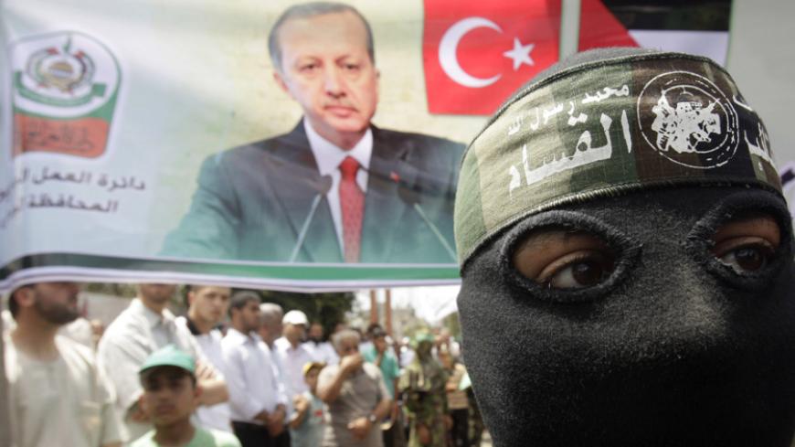 A masked member of Hamas stands in front of a banner depicting Turkey's Prime Minister Tayyip Erdogan during a protest in Central Gaza Strip June 4, 2010, against Israel's interception of Gaza-bound ships. Israeli marines stormed a  Turkish aid ship bound for Gaza on Monday and at least nine pro-Palestinian activists were killed, triggering a diplomatic crisis and an emergency session of the U.N. Security Council. REUTERS/Ibraheem Abu Mustafa (GAZA - Tags: POLITICS CIVIL UNREST) - RTR2ER4P