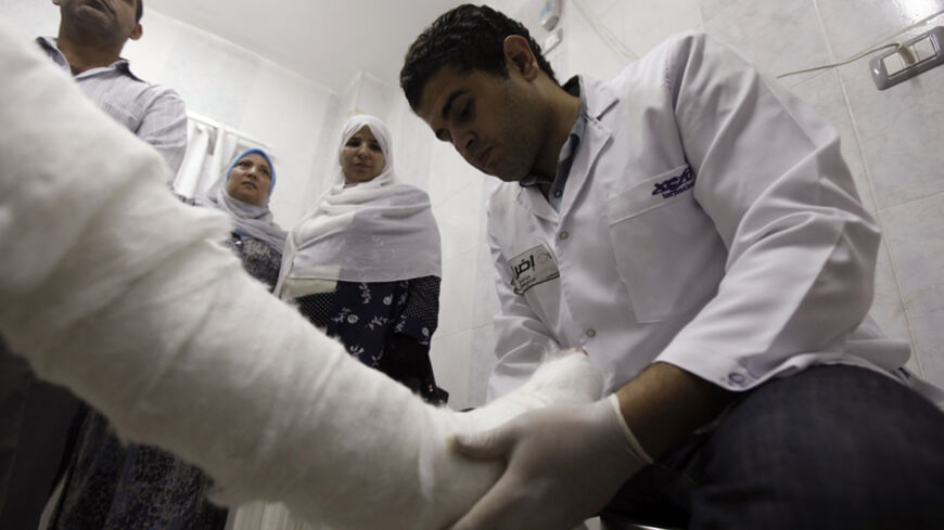 Doctor Karim Ahmed, 31, wearing a sticker that reads, "An open-ended strike for doctors, For patients before doctors", attends to a patient at Al-Moniera public hospital in Cairo October 2, 2012. Egypt's doctors began a partial strike on Monday with varied demands, including making the health budget 15 percent of the state budget, and improving security conditions to protect doctors and patients from assaults, said representatives from the Doctors' Syndicate.  REUTERS/Amr Abdallah Dalsh  (EGYPT - Tags: CIVI