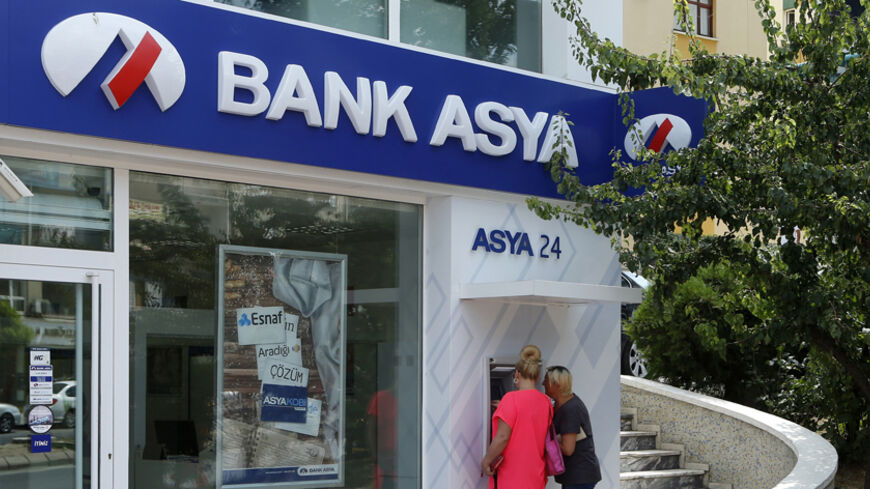 Customers use an ATM machine at a branch of Bank Asya in Ankara August 12, 2014. Turkish Islamic lender Bank Asya said its second-quarter net profit fell 81 percent to 10.6 million lira ($4.9 million) as its deposit base shrank and lending wilted under pressure from the government. The lender has seen its profits and capital base collapse since December when it found itself at the centre of a power struggle between Prime Minister Tayyip Erdogan and his political foe Fethullah Gulen, an Islamic cleric whose 