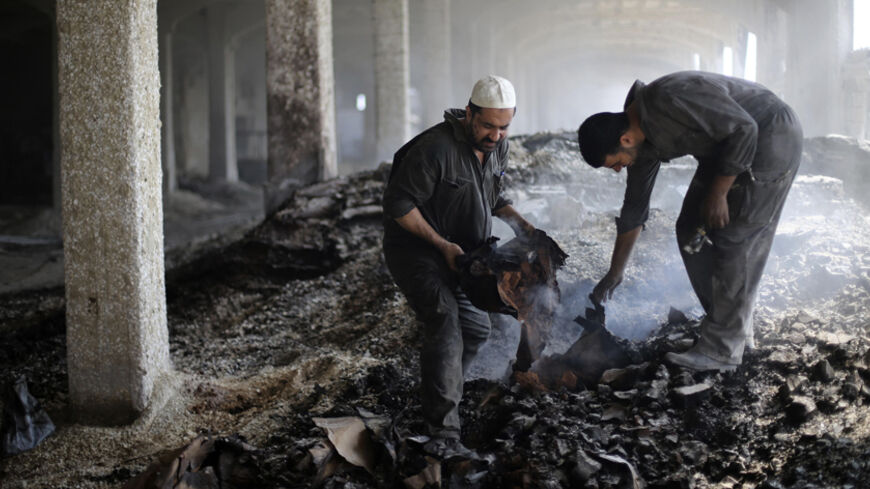 Palestinian workers gather debris inside al-Awdah food factory, which witnesses said was shelled and torched by the Israeli army during the offensive, in Deirl al-Balah in the central Gaza Strip August 14, 2014. A renewed truce between Israel and Hamas appeared to be holding on Thursday despite a shaky start, after both sides agreed to give Egyptian-brokered talks more time to try to end the Gaza war. REUTERS/Ibraheem Abu Mustafa (GAZA - Tags: POLITICS CIVIL UNREST) - RTR42EM3