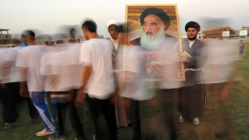Shi'ite volunteers, who have joined the Iraqi army to fight against militants of the Islamic State, formerly known as the Islamic State in Iraq and the Levant (ISIL), carry a picture of Grand Ayatollah Ali Sistani during a graduation ceremony after completing their field training in Najaf, August 16, 2014. School is out, but northern Baghdad's classrooms are packed - not with students, but with people who have travelled further than most to escape the Sunni militant onslaught splitting Iraq. REUTERS/Alaa Al