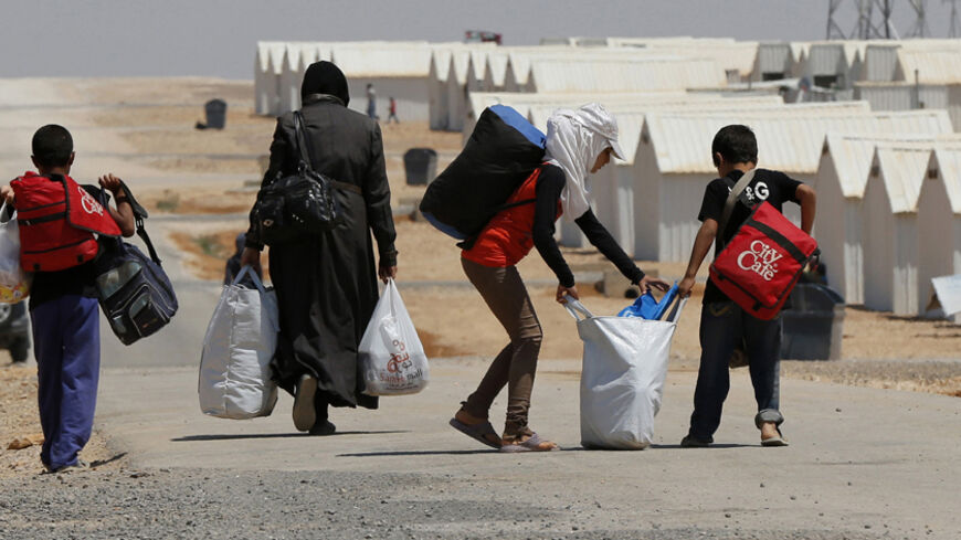 Newly-arrived Syrian refugees carry their belongings as they walk at Azraq refugee camp near Al Azraq area, east of Amman, August 19, 2014. The camp, which has a capacity to accommodate 50,000 people, has so far received around 10,498 refugees, according to a senior external relations officer at the United Nations. REUTERS/Muhammad Hamed (JORDAN - Tags: POLITICS CIVIL UNREST CONFLICT SOCIETY) - RTR42Z33
