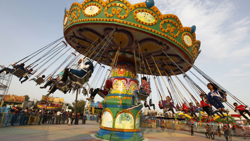 Residents take a ride at an amusement park as they celebrate the Muslim festival of Eid-al-Adha in Baghdad October 5, 2014. Muslims around the world celebrate Eid al-Adha to mark the end of the haj pilgrimage by slaughtering sheep, goats, camels and cows to commemorate Prophet Abraham's willingness to sacrifice his son, Ismail, on God's command.  REUTERS/Ahmed Saad (IRAQ - Tags: RELIGION) - RTR490NA