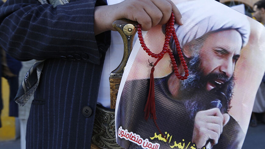 A Shi'ite protester carries a poster of Sheikh Nimr al-Nimr during a demonstration outside the Saudi embassy in Sanaa October 18, 2014. The Shi'ite Muslim minority in Saudi Arabia's Eastern Province have long felt marginalised by the Sunni ruling dynasty, and protests for greater rights as part of the 2011 Arab Spring brought a crackdown on both protesters and demands for reform. But now, death sentences for three Shi'ite Muslims, including prominent dissident cleric Nimr, suggest that the region's wider tu