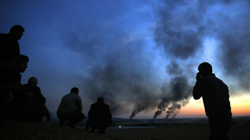 Kurdish refugees watch from a hilltop as thick smoke rises from the Syrian town of Kobani during heavy fighting between Islamic State and Kurdish Peshmerga forces, seen from near the Mursitpinar border crossing on the Turkish-Syrian border in the southeastern town of Suruc in Sanliurfa province October 26, 2014.  REUTERS/Yannis Behrakis (TURKEY - Tags: MILITARY CONFLICT POLITICS CIVIL UNREST) - RTR4BNM6