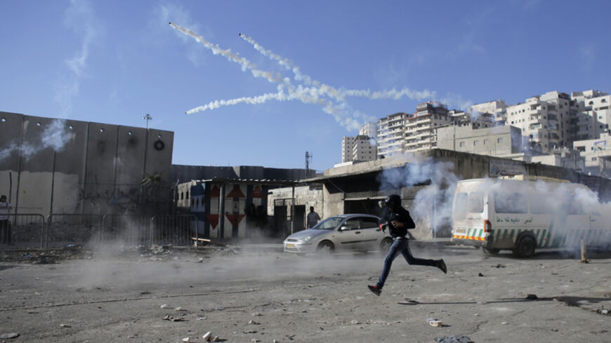 A Palestinian stone-thrower runs under tear gas during clashes with Israeli border police at a checkpoint between Shuafat refugee camp and Jerusalem November 6, 2014. For months, the streets of mainly Arab East Jerusalem, in the shadow of the Old City but where tourists seldom venture, have been ablaze, with daily clashes between armed Israeli police and Palestinians throwing rocks and Molotov cocktails.  REUTERS/Ammar Awad (JERUSALEM - Tags: POLITICS CIVIL UNREST) - RTR4D502