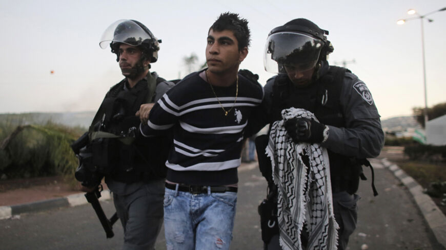 Israeli policemen detain an Arab youth during clashes at the entrance to the town of Kfar Kanna, north of Israel, November 8, 2014. Thousands took to the streets on Saturday hours after Khayr al-Din al-Hamdan was shot by police, after he attacked them as they came to arrest a relative.  REUTERS/Ammar Awad (ISRAEL - Tags: POLITICS CIVIL UNREST RELIGION) - RTR4DDLH
