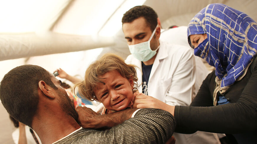 A medic examines a Kurdish Syrian refugee child inside a temporary medical facility for children on the Turkish-Syrian border near the southeastern town of Suruc in Sanliurfa province, in this September 24, 2014 file photo. Reuters photographers have chronicled Kurdish refugee crises over the years. In 1991 Srdjan Zivulovic documented refugees in Cukurca who had escaped a military operation by Saddam Hussein's government in Iraq aimed at "Arabising" Kurdish areas in the north. Hundreds of thousands fled int