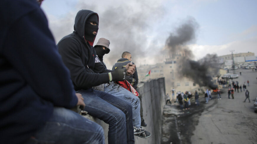 Palestinian protesters sit atop a section of Israel's controversial barrier that separates the West Bank town of Abu Dis from Jerusalem November 17, 2014. A Palestinian bus driver was found hanged inside his vehicle on Monday, an incident Israeli police described as a suicide but which the driver's family said they believed was an attack. Israeli police said the evidence suggested al-Ramouni had committed suicide, but rumors quickly spread in the Palestinian media that he had been killed by Jewish assailant