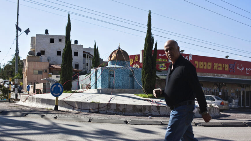 An Israeli Arab man walks past a replica of the Dome of the Rock mosque, in the Arab town of Kafr Qassem November 25, 2014. Israel is poised to pass one of the most divisive laws in its 66-year history, a bill that would declare it the homeland of the Jewish people only -- and further alienate its Arab minority. Political infighting over the measure is already threatening to tear apart Prime Minister Benjamin Netanyahu's governing coalition. REUTERS/Nir Elias (ISRAEL - Tags: POLITICS RELIGION) - RTR4FJQ9