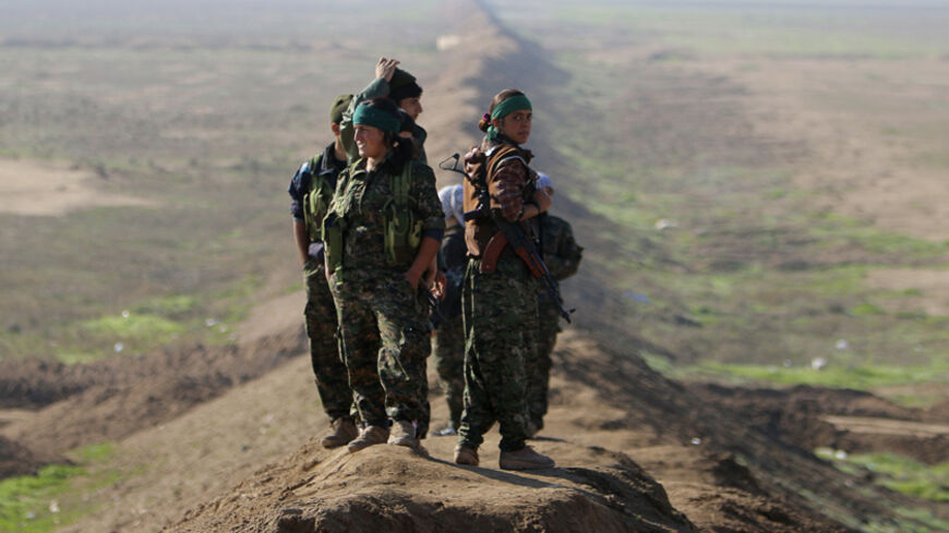 Female fighters of the Kurdish People's Protection Units (YPG) stand near the border between Syria and Iraq, close to the Iraqi town of Snoun December 22, 2014. On Sunday, Kurdish and Yazidi fighters battled to take the Sinjar back from Islamic State after breaking a months-long siege of the mountain above it. Seizing the town would restore the majority of territory Iraq's Kurds lost in Islamic State's surprise offensive in August Picture taken December 22, 2014. REUTERS/Stringer (IRAQ - Tags: POLITICS CIVI