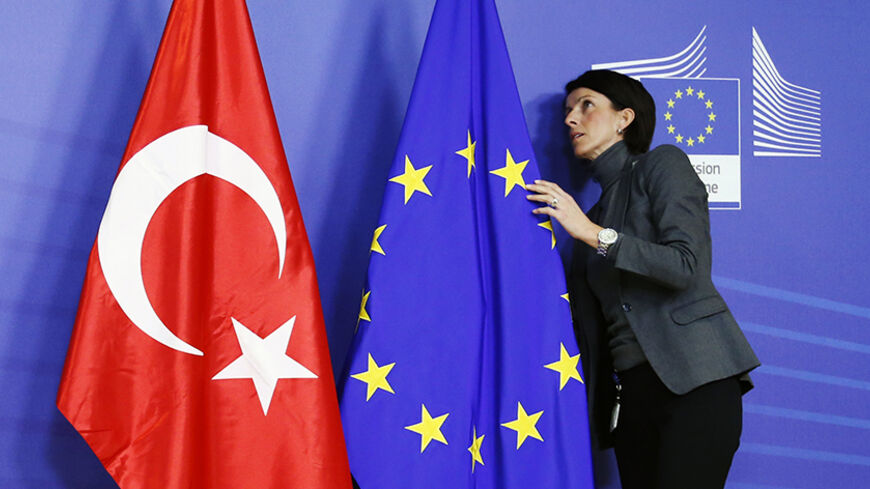 A staff adjusts European Union and Turkish (L) flags ahead of the arrival of Turkey's Prime Minister Tayyip Erdogan (not pictured) at the EU Commission headquarters in Brussels January 21, 2014. REUTERS/Francois Lenoir (BELGIUM - Tags: POLITICS) - RTX17NSQ