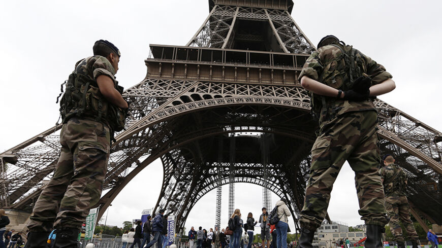 Soldiers stand by tourists as they patrol near the Eiffel Tower in Paris, May 8, 2013. President Francois Hollande said on Tuesday, May 7, that France was taking the threat from al Qaeda in the Islamic Maghreb (AQIM) seriously after a purported leader of the Islamist group called for attacks on French interests throughout the world.   REUTERS/Gonzalo Fuentes (FRANCE - Tags: TRAVEL CIVIL UNREST MILITARY POLITICS) - RTXZEPE