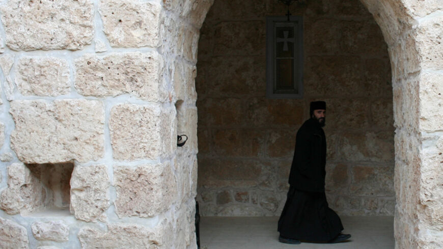 A Syriac Christian monk walks to attend a service at the ancient monastery of Mor Gabriel, 15 km (9 miles) from the town of Midyat, in Mardin province of southeast Turkey January 13, 2009. Tucked amid rugged hills where mosques and minarets are silhouetted in the distance, the fifth century Mor Gabriel monastery stands out as a relic of another era when hundreds of thousands of Syriac Christians lived and worshipped in Turkey. But a land dispute between Mor Gabriel and neighbouring villages is threatening t