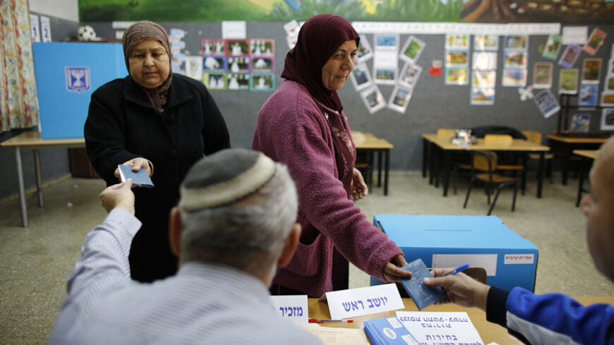 Women have their identities checked before voting for the parliamentary election at a polling station in the northern Israeli Arab town of Sakhnin January 22, 2013. Israelis voted on Tuesday in an election that is expected to hand hawkish Prime Minister Benjamin Netanyahu a third term, opening the way for a showdown with Iran and bolstering opponents of Palestinian statehood. REUTERS/Ammar Awad (ISRAEL - Tags: POLITICS ELECTIONS) - RTR3CT0S