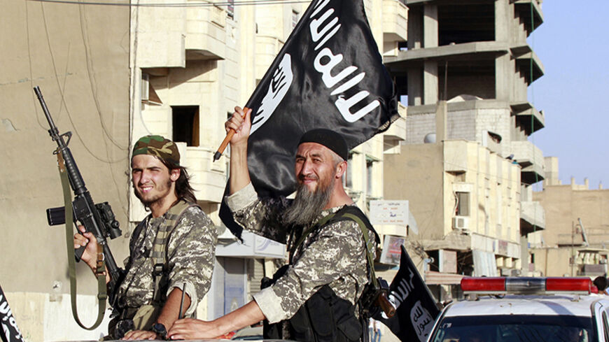 Militant Islamist fighters wave flags as they take part in a military parade along the streets of Syria's northern Raqqa province June 30, 2014. The fighters held the parade to celebrate their declaration of an Islamic "caliphate" after the group captured territory in neighbouring Iraq, a monitoring service said. The Islamic State, an al Qaeda offshoot previously known as Islamic State in Iraq and the Levant (ISIL), posted pictures online on Sunday of people waving black flags from cars and holding guns in 