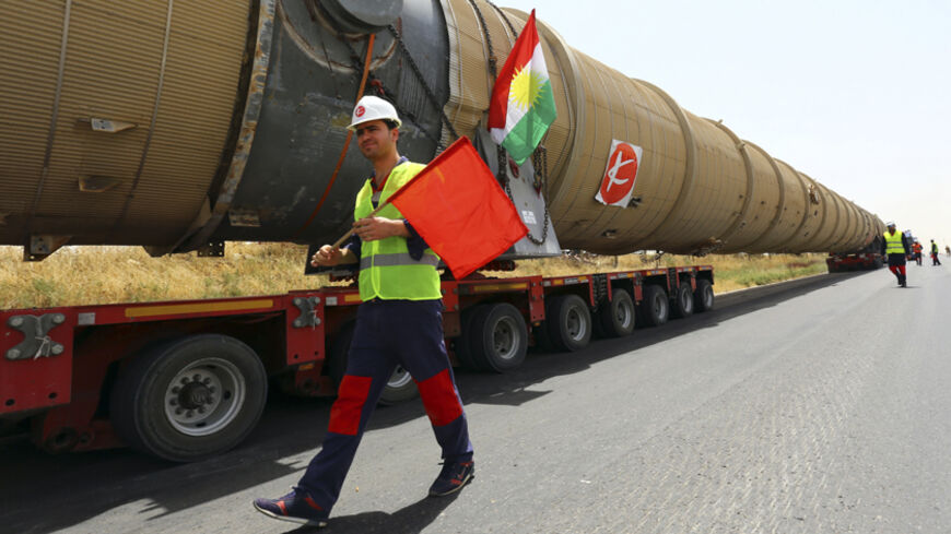 A worker walks past a section of an oil refinery, which is being brought on a truck to Kalak refinery in the outskirts of Arbil, in Iraq's Kurdistan region, July 14, 2014. REUTERS/Stringer (IRAQ - Tags: ENERGY) - RTR3YN77