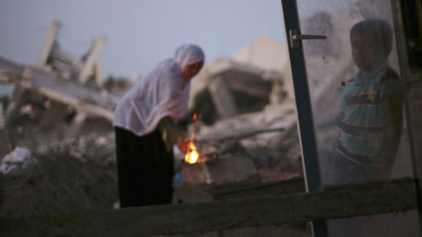 A Palestinian woman makes coffee on a fire outside her makeshift shelter near the ruins of her house, which witnesses said was destroyed during the Israeli offensive, in Al Mughraga village in the south of Gaza City September 8, 2014.  An open-ended ceasefire between Israel and Hamas-led Gaza militants, mediated by Egypt, took effect on August 26 after a seven-week conflict. It called for an indefinite halt to hostilities, the immediate opening of Gaza's blockaded crossings with Israel and Egypt, and a wide