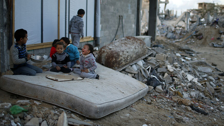 Palestinian children play on a mattress near the ruins of houses which witnesses said were destroyed by Israeli shelling during the most recent conflict between Israel and Hamas, in the east of Gaza City December 1, 2014. According to housing minister Mufeed al-Hasayna, Gaza needs 8,000 tonnes of cement a day to meet demand. A new system set up with the United Nations to comply with Israeli requirements lets through at most 2,000, he said. At that rate, reconstruction would take more than 30 years, said Has