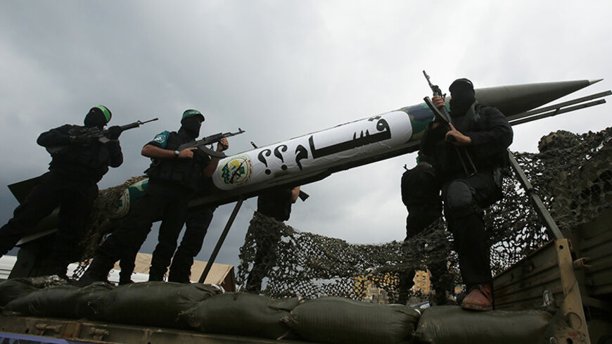 Palestinian members of al-Qassam Brigades, the armed wing of the Hamas movement, display a home-made Qassam rocket during a military parade marking the 27th anniversary of Hamas' founding, in Gaza City December 14, 2014.  REUTERS/Suhaib Salem (GAZA - Tags: POLITICS MILITARY ANNIVERSARY) - RTR4HXKR
