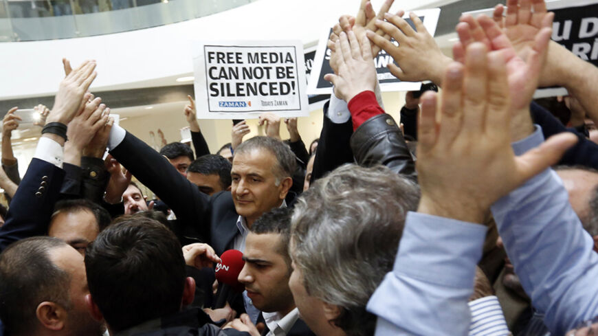Zaman editor-in-chief Ekrem Dumanli (C), escorted by plainclothes police officers, is cheered on by his colleagues as he leaves the headquarters of Zaman daily newspaper in Istanbul December 14, 2014. Turkish police raided media outlets close to U.S.-based Muslim cleric Fethullah Gulen on Sunday and detained 23 people nationwide in operations against what President Tayyip Erdogan says is a network conspiring to topple him.    REUTERS/Murad Sezer (TURKEY - Tags: CRIME LAW POLITICS MEDIA TPX IMAGES OF THE DAY