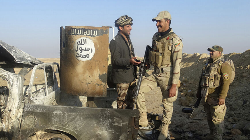 Iraqi security forces stand on a destroyed vehicle belonging to the Islamic State militants on the outskirt of Ramadi December 21, 2014. Picture taken December 21, 2014.  REUTERS/Stringer (IRAQ - Tags: CIVIL UNREST MILITARY POLITICS) - RTR4J6YH