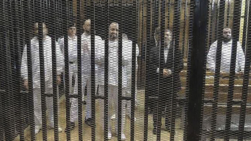 Ousted former Egyptian president Mohamed Mursi (2nd R) stands with other senior figures of the Muslim Brotherhood in a cage in a courthouse on the first day of his trial, in Cairo, November 4, 2013. Ousted Egyptian leader Mursi, given his first public forum since his overthrow, in a trial where he could face execution, declared on Monday he was still Egypt's legitimate president and shouted: "Down with military rule!" It was the first public sighting of Mursi since he was ousted by the army on July 3 after 