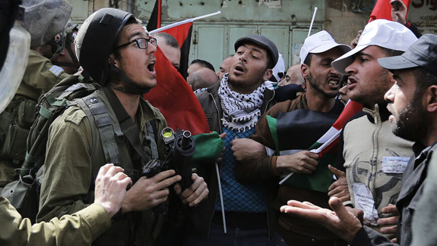 Palestinian protesters confront an Israeli soldier during clashes at a demonstration against the closure of Shuhada street to Palestinians, in the West Bank city of Hebron February 21, 2014. Hundreds of protesters, including foreign activists, gathered on Friday to mark the 20th anniversary of the closure of the street by the Israeli army in 1994 after Baruch Goldstein, an Israeli settler, shot dead 29 Palestinians inside Hebron's Al Ibrahimi Mosque. REUTERS/Ammar Awad (WEST BANK - Tags: POLITICS CIVIL UNRE